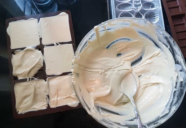 Moulding White Chocolate Spooning white chocolate into moulds. A big bowl of white chocolate and some moulds.
