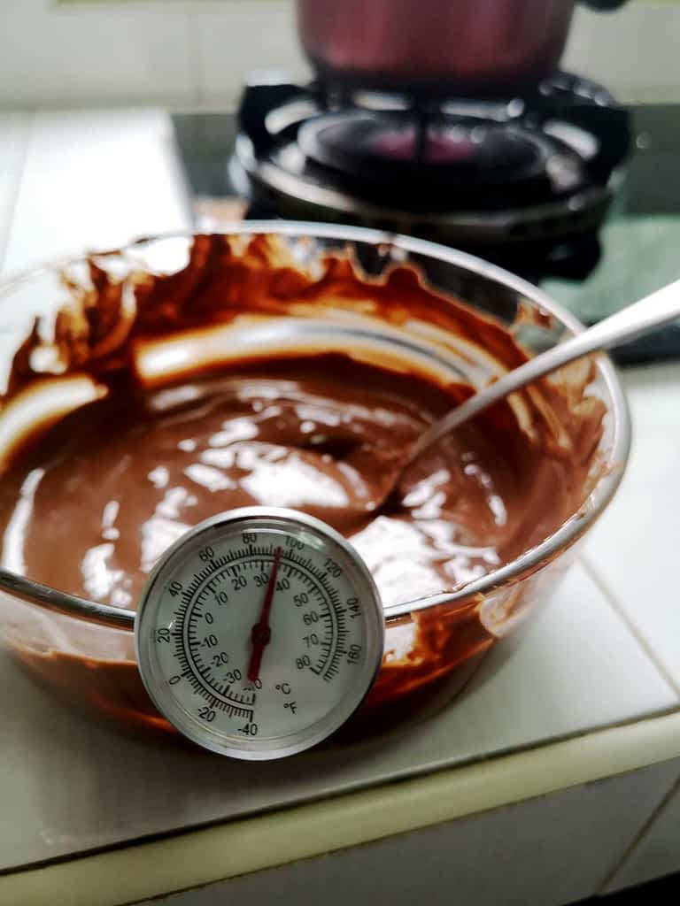 Tempering-on-stove A bowl of chocolate with a thermometer being tempered.